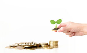 金貨の山に植物の芽を植える手